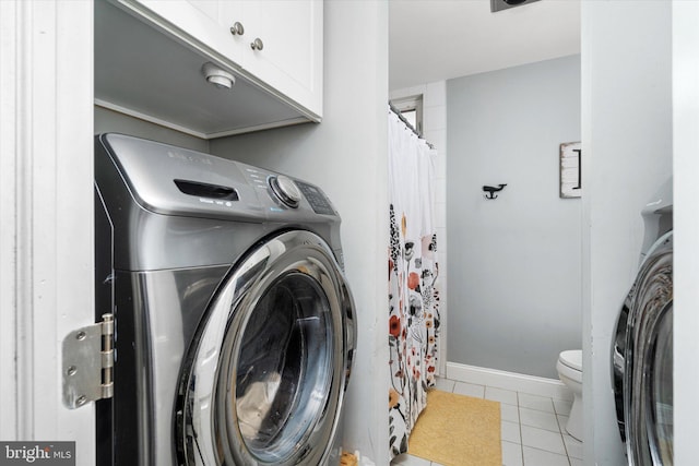 clothes washing area with washer / dryer and light tile patterned floors