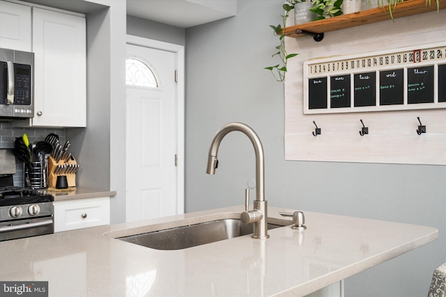 kitchen featuring white cabinets, appliances with stainless steel finishes, decorative backsplash, and sink