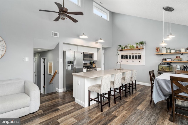 kitchen with white cabinetry, a kitchen island with sink, pendant lighting, stainless steel appliances, and a breakfast bar area