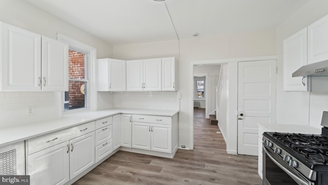 kitchen featuring decorative backsplash, plenty of natural light, white cabinets, and stainless steel gas stove