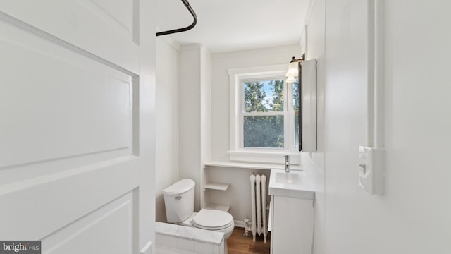 bathroom with wood-type flooring, radiator, sink, and toilet