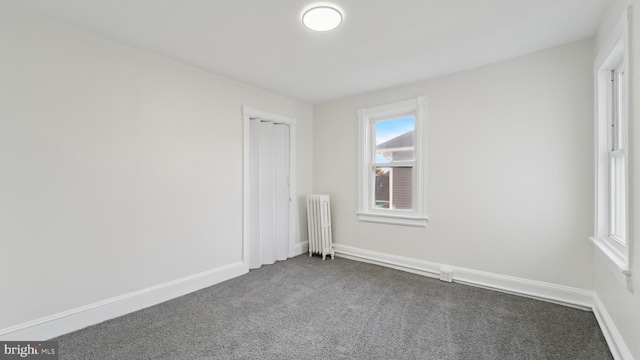 unfurnished room with radiator and dark carpet