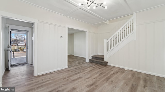 unfurnished living room featuring coffered ceiling, hardwood / wood-style flooring, and an inviting chandelier