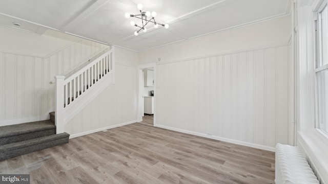 unfurnished living room featuring radiator heating unit, light hardwood / wood-style flooring, and a notable chandelier