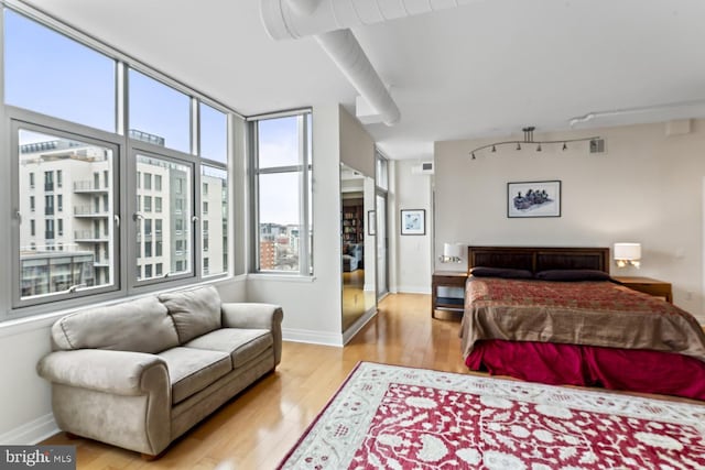 bedroom with light hardwood / wood-style flooring and track lighting