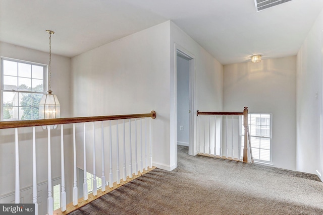 hall featuring carpet flooring and a chandelier