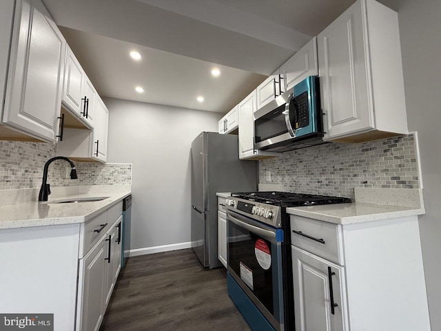 kitchen with light stone countertops, white cabinets, appliances with stainless steel finishes, dark hardwood / wood-style flooring, and sink