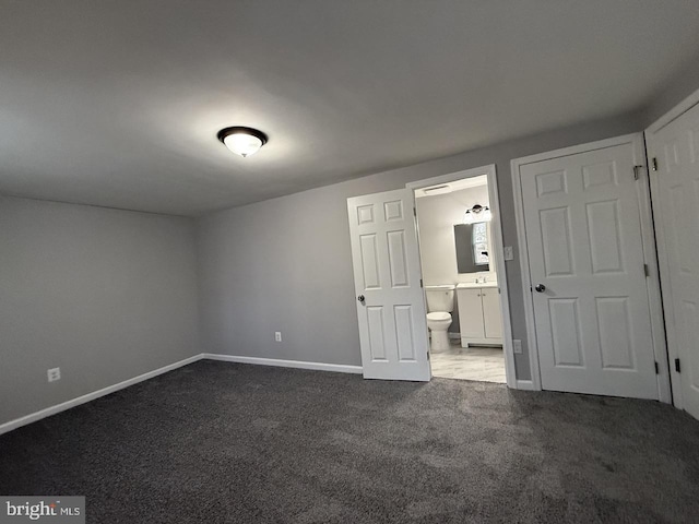 unfurnished bedroom with connected bathroom and carpet flooring