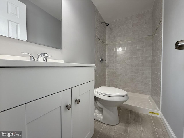 bathroom featuring tiled shower, toilet, and vanity