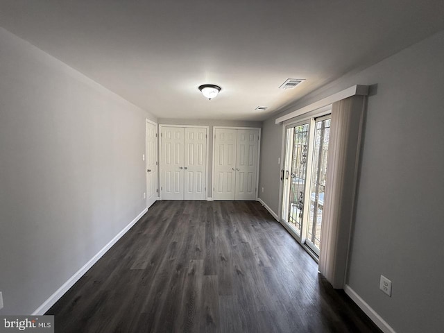 interior space with dark hardwood / wood-style floors, access to outside, and multiple closets