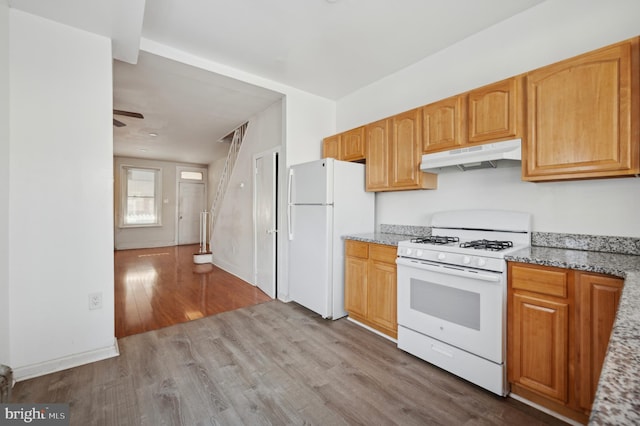 kitchen featuring light stone counters, white appliances, ceiling fan, and light wood-type flooring