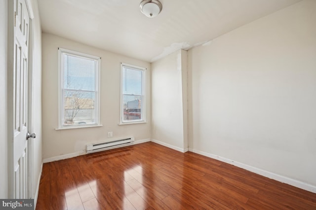 empty room featuring a baseboard heating unit and hardwood / wood-style flooring