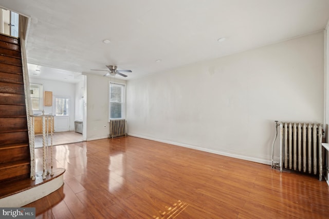 unfurnished living room featuring ceiling fan, radiator, and light hardwood / wood-style floors