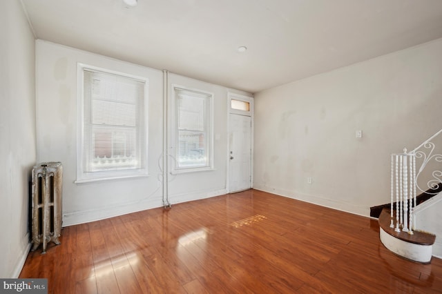 unfurnished living room with radiator and hardwood / wood-style floors