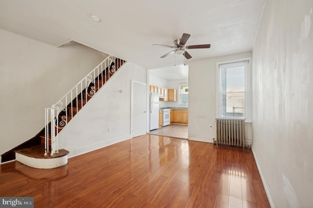 unfurnished living room featuring ceiling fan, light hardwood / wood-style flooring, and radiator heating unit