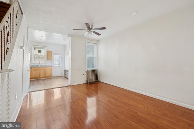 unfurnished living room featuring radiator, ceiling fan, light hardwood / wood-style flooring, and sink