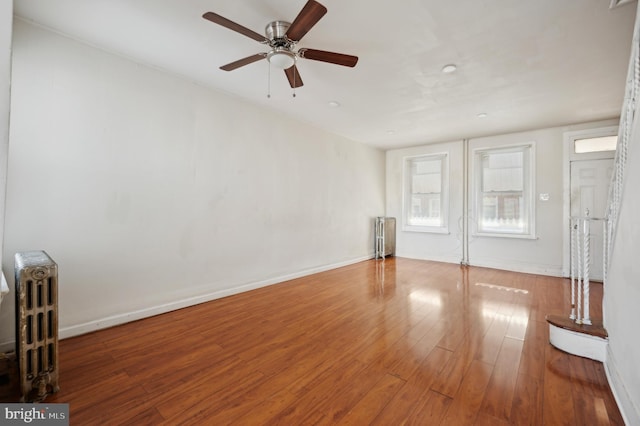 unfurnished living room featuring ceiling fan, wood-type flooring, and radiator heating unit