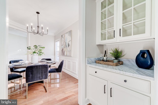 dining space with an inviting chandelier, crown molding, and light wood-type flooring