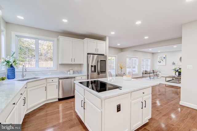 kitchen featuring stainless steel appliances, light stone countertops, sink, and white cabinets