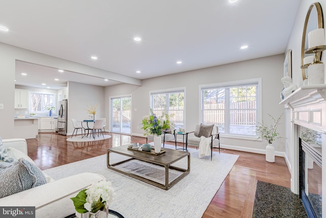 living room featuring hardwood / wood-style floors, beam ceiling, and a premium fireplace