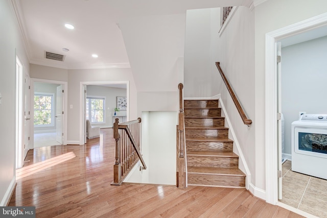 stairway with wood-type flooring, washer / dryer, and crown molding