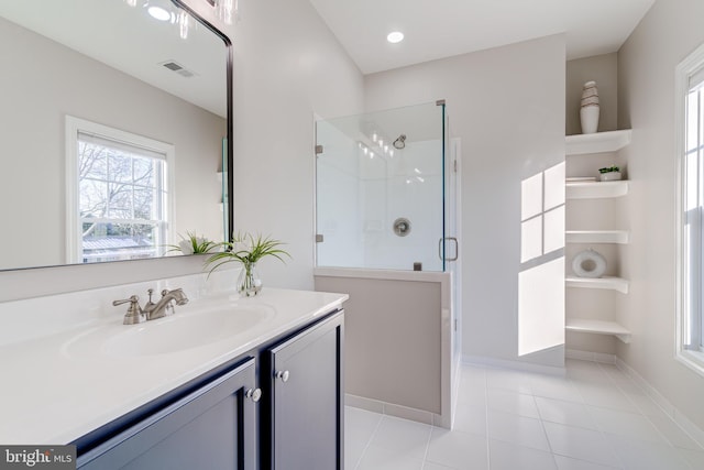 bathroom with a shower with door, vanity, and tile patterned floors