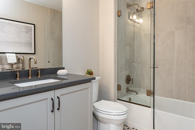 full bathroom with toilet, bath / shower combo with glass door, and vanity