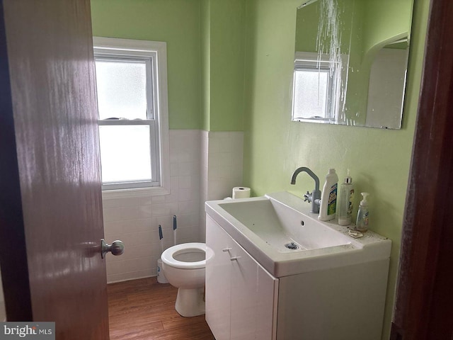 bathroom with toilet, plenty of natural light, wood-type flooring, and vanity