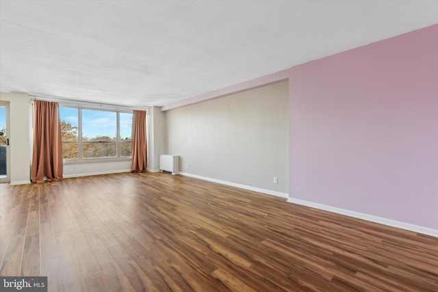 unfurnished living room featuring wood-type flooring and radiator