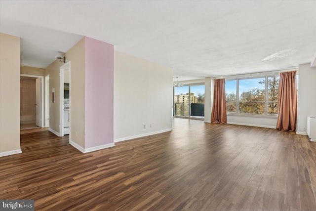 unfurnished living room with radiator heating unit, dark hardwood / wood-style floors, and a notable chandelier