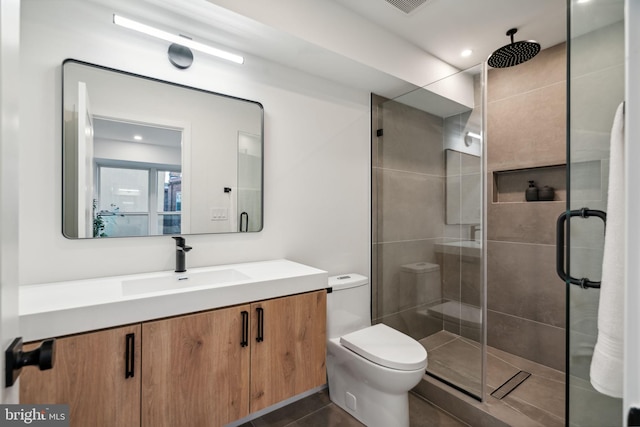 bathroom featuring vanity, a shower with shower door, and toilet