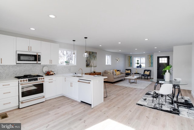 kitchen with pendant lighting, sink, white appliances, white cabinets, and kitchen peninsula