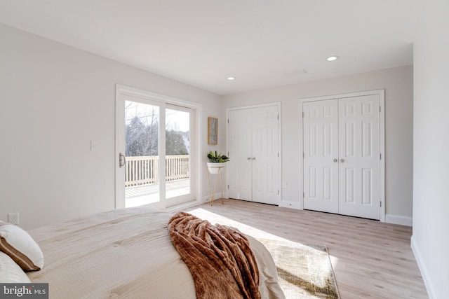 bedroom featuring access to exterior, light hardwood / wood-style flooring, and two closets