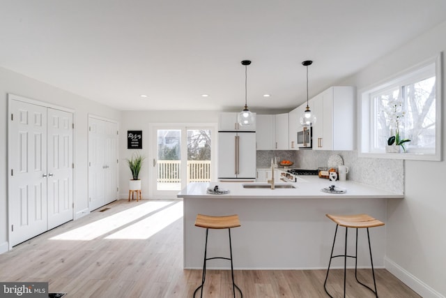 kitchen featuring sink, a breakfast bar, high end fridge, white cabinetry, and kitchen peninsula