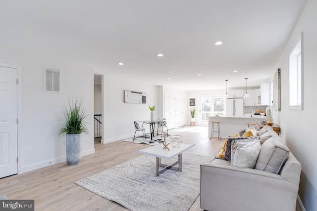 living room featuring a wall mounted air conditioner and light hardwood / wood-style floors