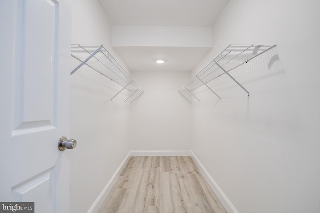 walk in closet with light hardwood / wood-style floors