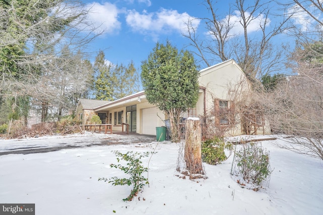 view of snowy exterior featuring a garage and covered porch