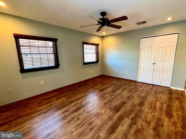 unfurnished bedroom featuring multiple windows, a closet, ceiling fan, and dark hardwood / wood-style flooring