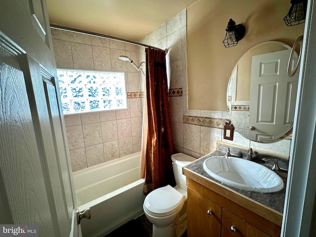 full bathroom with tile walls, toilet, vanity, and shower / tub combo