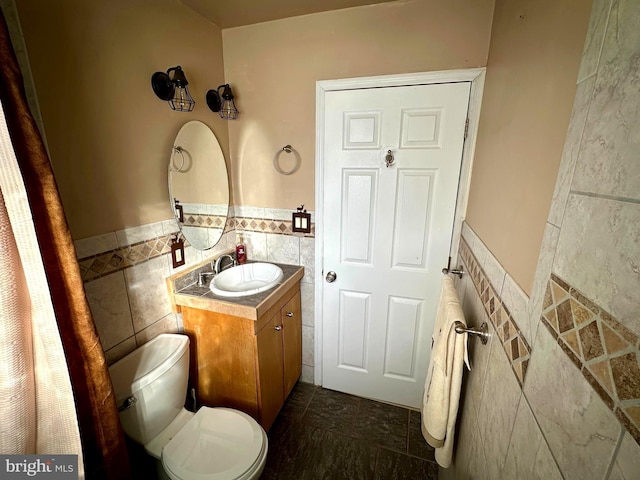 bathroom featuring toilet, vanity, and tile walls