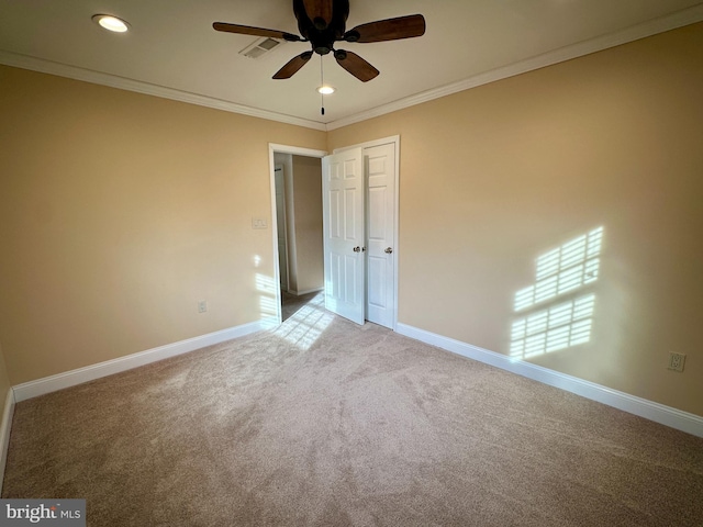 carpeted spare room with ceiling fan and ornamental molding