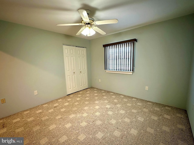 unfurnished bedroom with ceiling fan, a closet, and carpet floors