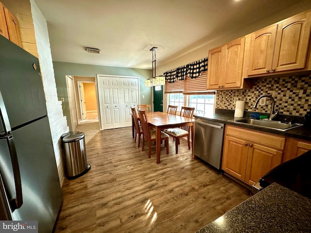 kitchen with dishwasher, hanging light fixtures, sink, dark wood-type flooring, and black fridge