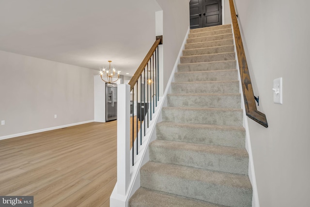 stairway featuring hardwood / wood-style flooring and a chandelier