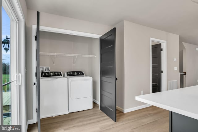 laundry room with washer and clothes dryer, a healthy amount of sunlight, and light hardwood / wood-style flooring