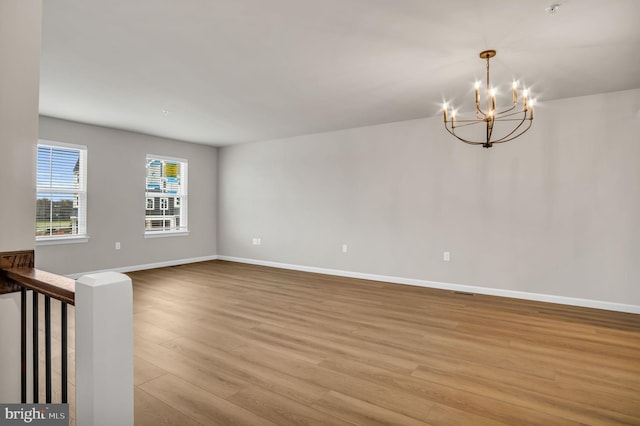 unfurnished room featuring light wood-type flooring and a notable chandelier