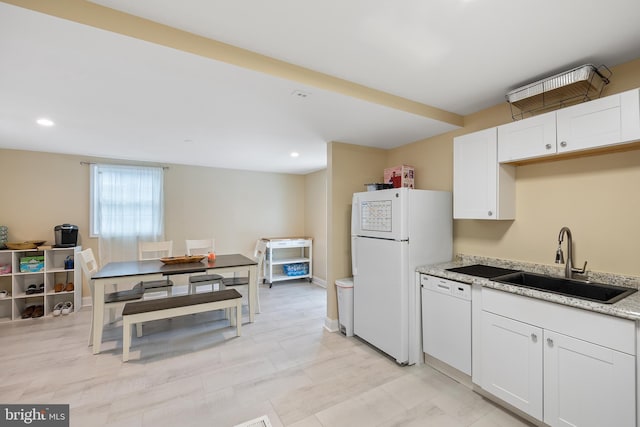 kitchen with light stone countertops, white cabinetry, sink, and white appliances