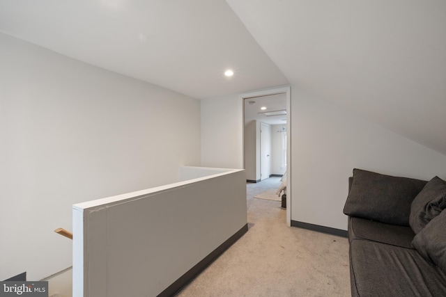 hall featuring light colored carpet and lofted ceiling