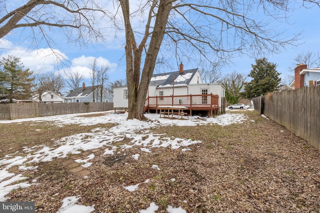 snow covered rear of property with a wooden deck