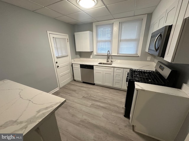 kitchen featuring stainless steel appliances, a drop ceiling, light wood-type flooring, white cabinets, and sink